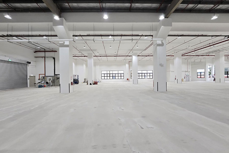 A spacious industrial facility ready for handover, with clean floors, high ceilings, and a polished finish to mark project completion.